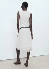 Falda midi de encaje blanco con diseño recto y bajo asimétrico con terminaciones en pico. Posee forro interior y cintura elástica.