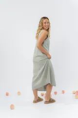 Vestido midi de lino en color verde seco, con escote en V, diseño sin mangas y cierre frontal con botones de madera. Presenta un corte recto y fluido con una abertura frontal en el bajo.