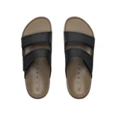 Sandalias tipo slide de dos tiras ajustables con velcro, marca Reef. La capellada es negra y la suela es de goma EVA en color marrón claro. El nombre de la marca está grabado en relieve en la tira lateral.