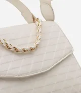 Bolso negro de tamaño mediano, con correa superior fija y correa bandolera, solapa delantera acolchada con patrón de rombos y cierre de botón a presión.