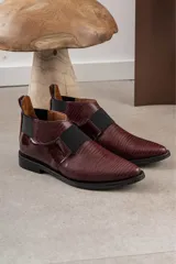 Bota corta color borgoña con textura de reptil, puntera fina, elástico negro en el empeine y talón descubierto.