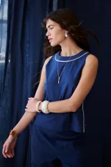 Top sin mangas color rosa pálido, con cuello redondo y vivos en color marrón oscuro en el cuello y a lo largo de las costuras laterales.