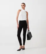Pantalón legging negro de viscosa con elastano, corte cigarrillo, con cierre y detalles en material sintético.