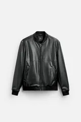 Cazadora bomber negra de efecto piel, corte relaxed fit, con cuello y puños de rib elástico, cierre frontal con cremallera, bolsillos laterales de doble vivo y bolsillo interior.