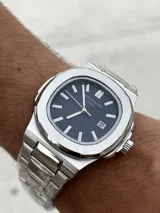 Reloj de pulsera Patek Philippe Nautilus con caja y brazalete de acero inoxidable, esfera azul con patrón horizontal en relieve y movimiento automático.