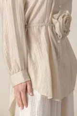 Camisa larga italiana color crudo, de calce holgado, con lazo en la cintura con flor y mangas largas con presilla para sujetar.