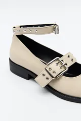 Zapato tipo zueco negro charol con punta fina, doble tira con hebillas metálicas y pulsera al tobillo con tachas.