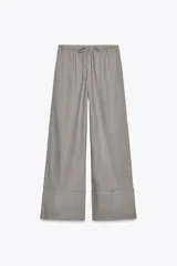 Pantalón palazzo color ladrillo, confeccionado en lino 100%, de tiro medio, cintura ajustable con cordones, bolsillos laterales ocultos y pierna ancha.