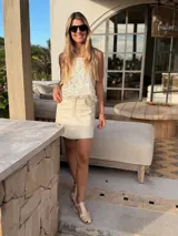 Top color crema con detalles dorados y breteles de cuero artesanales.