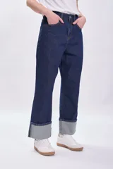 Pantalón de jean azul oscuro con bajo doblado.