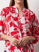 Blusa de gasa estampada con flores rojas y blancas, marca Floral & Ivy. Tiene cuello a la base con escote en V y mangas tres cuartos regulables con presilla y botón.
