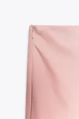 Falda larga de tiro medio color rosa, confeccionada en hilatura con viscosa y lyocell. Bajo asimétrico acabado en línea evasé. Cierre lateral con cremallera oculta en costura.