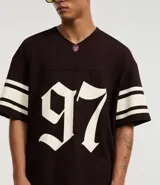 Remera deportiva azul con cuello en V, mangas cortas y estampado de fútbol americano con el número 97 en blanco y rayas blancas en las mangas.