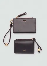 Monedero pequeño color beige con efecto piel y detalle de abalorios. Tiene cierre de solapa con botón magnético, bolsillo interior y bolsillo lateral con cierre de cremallera.