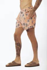 Short de baño con estampado de hojas de palmera en tonos beige, verde y naranja.