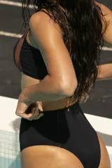 Top de bikini con estampado geométrico en tonos rosados y detalle de contorno en color verde azulado.