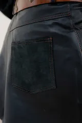 Minifalda negra de cuero con bolsillos delanteros y costuras decorativas en color ocre.