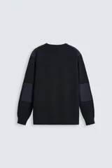 Jersey negro de punto con cuello redondo y manga larga. Presenta parches combinados en hombros y codos.