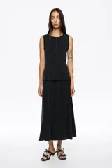 Falda midi de corte línea A confeccionada en mezcla de cupro color negro. Presenta costuras verticales con pespuntes decorativos que realzan la silueta.