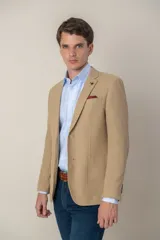 Saco sport color beige de jersey, corte slim fit, con cierre de dos botones, solapa de muesca, bolsillo de parche en el pecho y bolsillos delanteros con solapa.