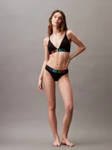 Conjunto Calvin Klein compuesto por corpiño triangular y colaless negros, con cintura elástica con logo de la marca en colores del arcoíris.