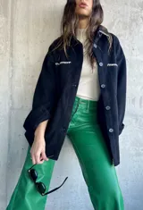 Abrigo negro de corte elegante, con detalles de despunte y cierre frontal.