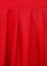 Falda midi evasé color rojo, con diseño de tablas y cierre de cremallera invisible en el lateral.