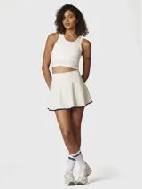 Falda skort blanca con borde negro en el dobladillo, confeccionada en tejido reciclado con tecnología Aircool. Incluye un short integrado con bolsillo.