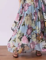 Vestido largo de gasa estampada con flores en tonos celeste, rosa y verde. Tiene cuello halter con abertura en forma de ojal, corte en la cintura con faja plisada y abertura central en la espalda con cierre invisible.