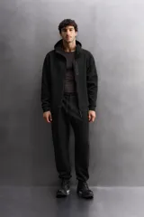 Sudadera con capucha color marrón topo, de corte regular fit, confeccionada en tejido técnico compacto de algodón con elasticidad. Cuenta con cuello subido, manga larga con bolsillo, bolsillos frontales con cierre de cremallera y acabados con rib del mismo tejido.