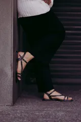 Sandalias chatitas negras de cuero con múltiples tiras finas y tachas doradas.