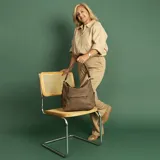Cartera negra de cuero sintético con apertura superior y cierre con solapa. Tiene un bolsillo frontal con broche magnético y cierre, dos bolsillos internos y un bolsillo divisor en el forro. Incluye bolsillos laterales con cierre y correa larga regulable.