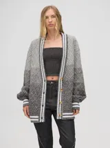 Cardigan tejido de punto con patrón de rombos en degradé de grises y blanco. Tiene corte oversize, mangas largas y cierre frontal con botones.