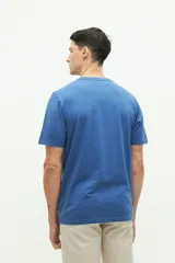 Remera azul de manga corta con cuello redondo y estampado de playa con sombrilla, reposera, balde y pala.