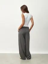 Pantalón gris oscuro de vestir con pinzas, corte amplio y tiro alto.