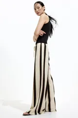 Pantalón de punto color crema con rayas verticales negras y marrones, de corte holgado y tiro alto, con cintura elástica y cordón ajustable.