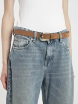 Cinturón de cuero gamuzado color camel o marrón claro, con hebilla metálica plateada de estilo western con bordes cincelados.