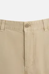 Pantalón color arena de corte recto, confeccionado en tejido de algodón con estructura canvas. Cuenta con cintura ajustable con trabillas laterales, bolsillos frontales y traseros de vivo. Cierre frontal con cremallera y botón.