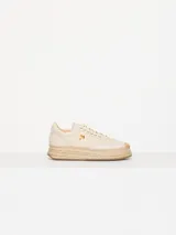 Zapatilla color crema con aplique de labial y logo dorado en el lateral, confeccionada en cuero y rafia, con suela de yute.
