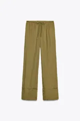 Pantalón palazzo color ladrillo confeccionado en lino 100%, de tiro medio con cintura ajustable con cordones, bolsillos laterales ocultos en costura y pierna ancha.
