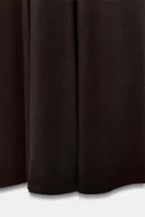 Vestido largo color marrón oscuro, con cuello alto y corte al cuerpo en la parte superior, y falda acampanada con pliegues. Presenta tirantes finos que dejan los hombros al descubierto.