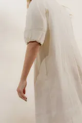 Vestido largo rojo con escote en V, mangas abullonadas con elástico en el puño y detalle de pespunte en contraste. Presenta un canesú con efecto punto smock y bolsillos laterales.