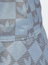 Gorro tipo bucket Adidas color celeste con estampado de monogramas con el logo del trifolio en gris.