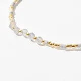 Pulsera de cuentas blancas con detalles en dorado, ajustable.