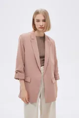 Blazer color rosa viejo, de corte recto, con solapas y mangas 3/4 con botón decorativo.