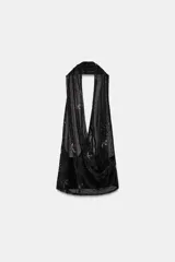 Top halter negro de tejido tipo tul, con escote fluido y espalda descubierta. Presenta bordados con aplicación de abalorios plateados en forma de estrellas o motivos celestes.