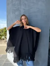 Ruana negra tejida en lana con aplique de cuero en la espalda y flecos en el ruedo.