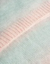Bufanda tejida con efecto degradé en tonos pastel: rosa, celeste, gris y blanco.