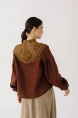 Blusa color ladrillo con cuello alto de crochet y lazos para ajustar. Mangas largas abullonadas con puños elásticos.