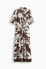Vestido midi camisero color marrón con estampado floral blanco, cuello camisero, botonadura frontal y mangas cortas. Incluye cinturón extraíble para atar.